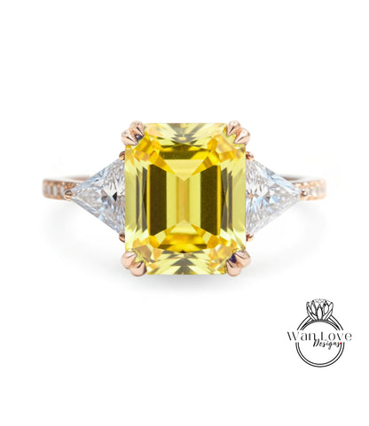 A yellow diamond ring with a large central diamond and two smaller diamonds on either side.