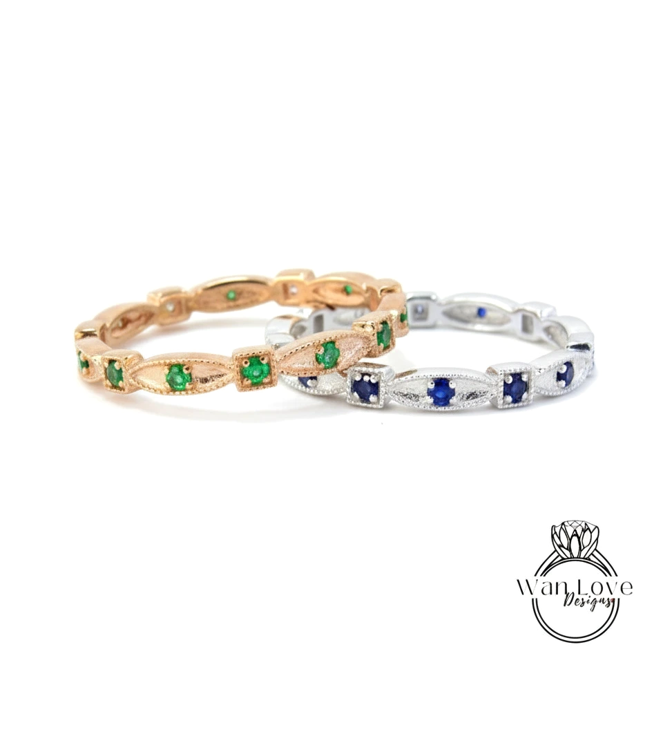 two rings with green and blue gemstones set in a decorative pattern.