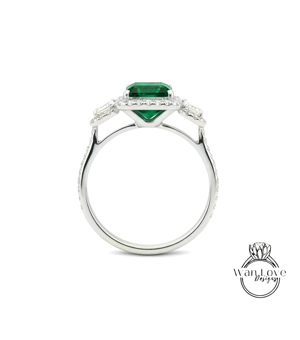 A silver ring with a large green gemstone, likely an emerald, set in the center.
