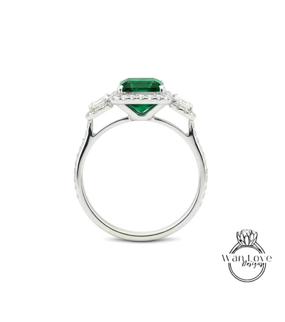 A silver ring with a large green gemstone, likely an emerald, set in the center.