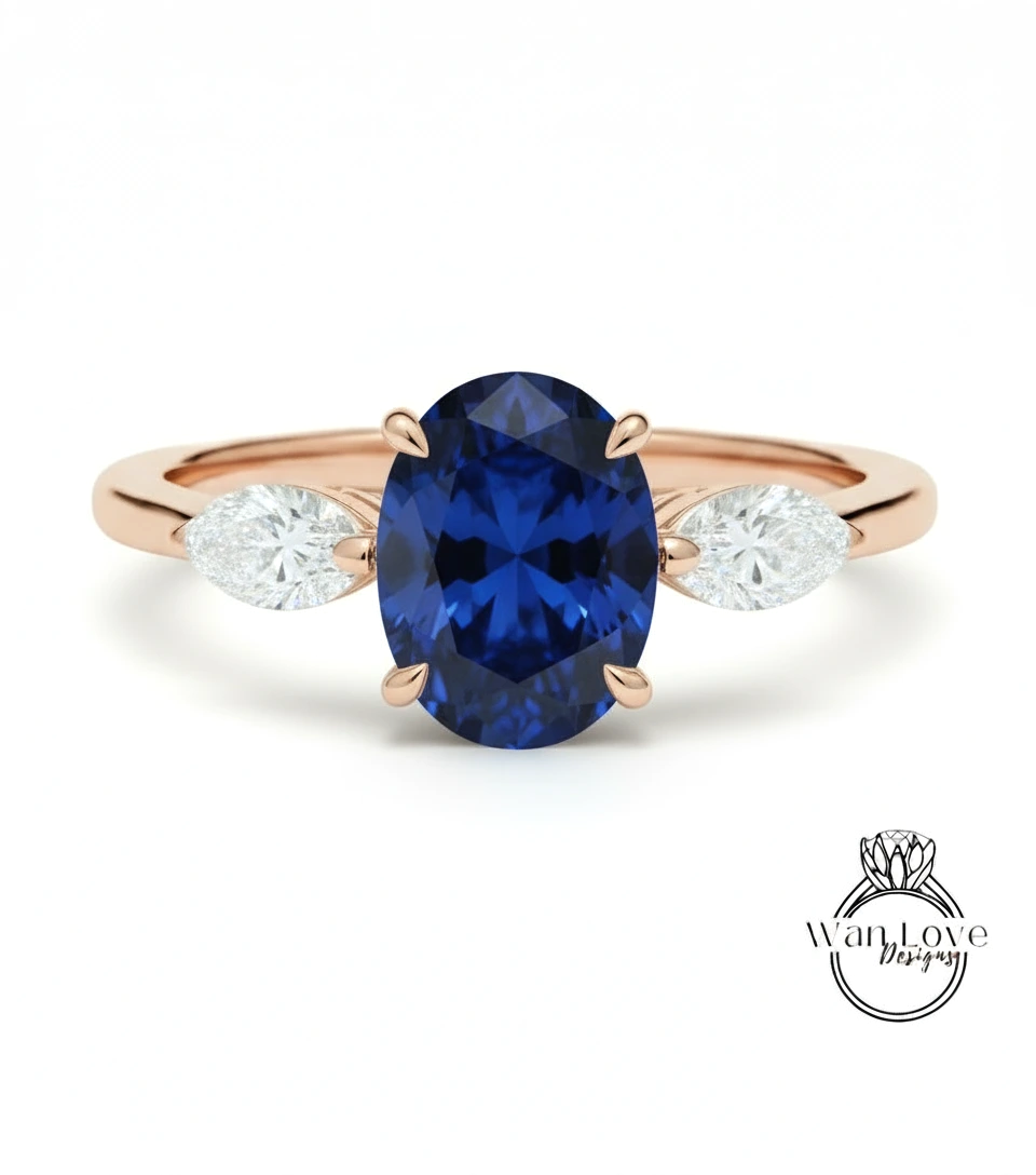 A gold ring with a large blue sapphire gemstone in the center, flanked by two smaller diamonds on either side.