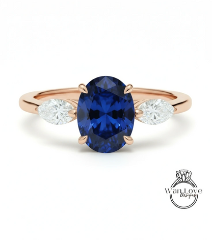 A gold ring with a large blue sapphire gemstone in the center, flanked by two smaller diamonds on either side.