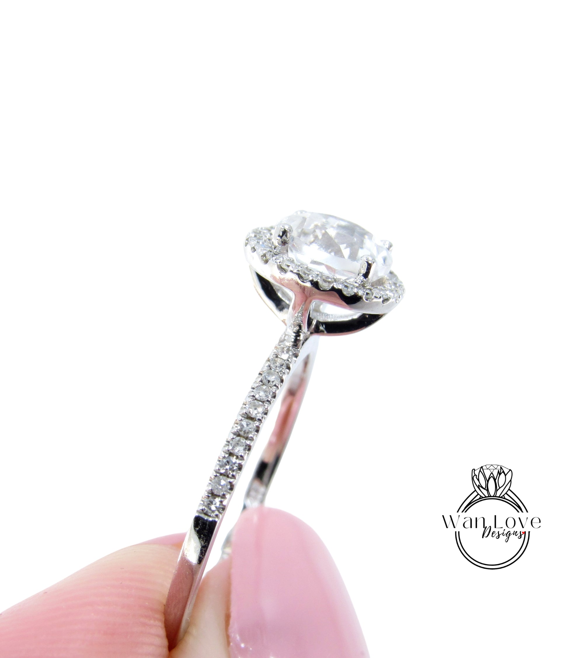 A close-up of a diamond engagement ring being held in a hand, with a focus on the center stone and the intricate details of the ring.