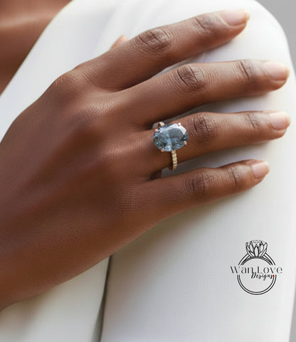 A close-up of a hand wearing a large blue gemstone ring on the ring finger.