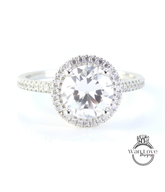 A close-up view of a diamond engagement ring with a large, round brilliant-cut diamond set in a halo of smaller diamonds.