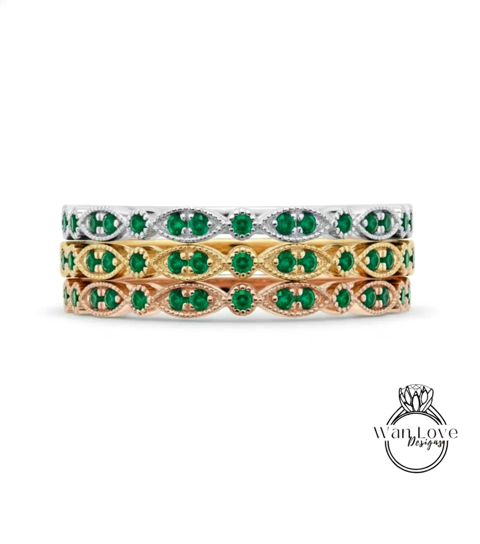 A stack of three rings with green gemstones set in a decorative pattern.