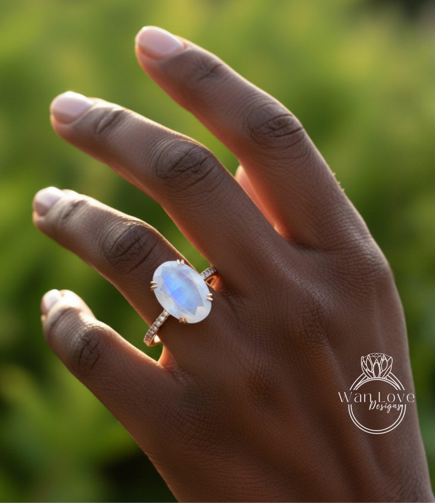 A close-up of a hand wearing a ring with a large moonstone.