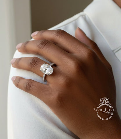 A close-up of a person's hand wearing a large diamond engagement ring on the ring finger.