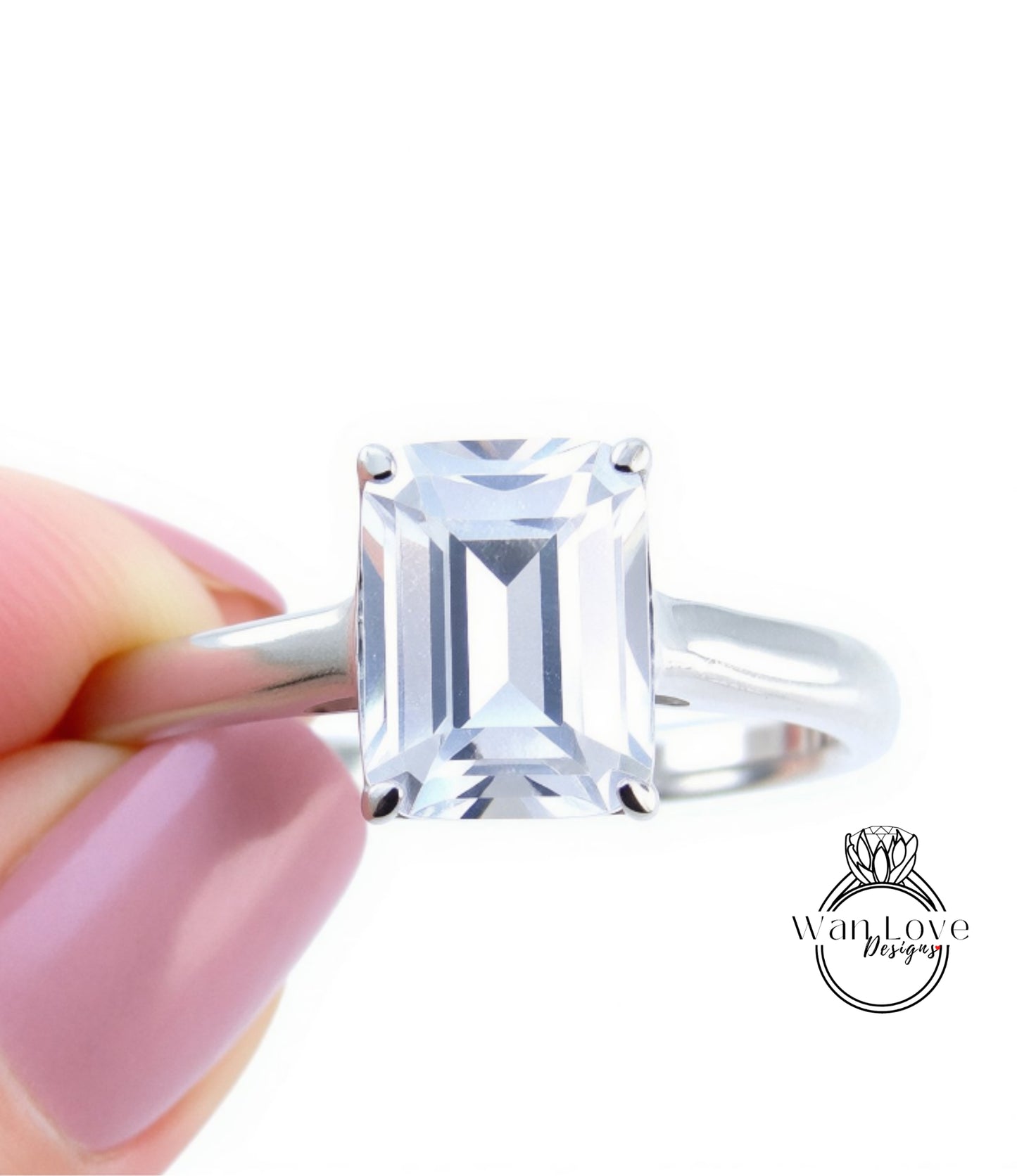 A close-up image of a person's hand holding a diamond engagement ring with a large, clear gemstone.