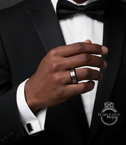 A close-up of a man's hand wearing a black tuxedo and a wedding ring, with a logo for Wan Love Designs visible in the background.
