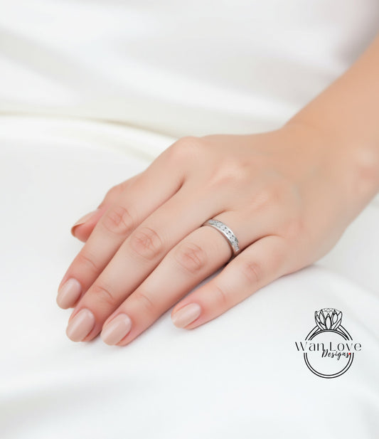 A close-up of a hand wearing a silver ring on the ring finger.