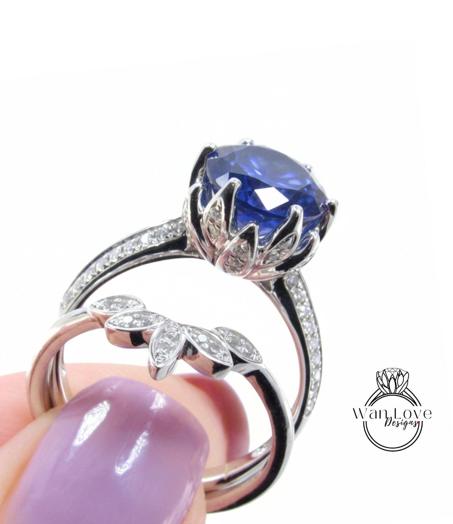 A close-up of a person's hand holding a silver ring with a large blue gemstone, and another ring with a smaller blue gemstone.