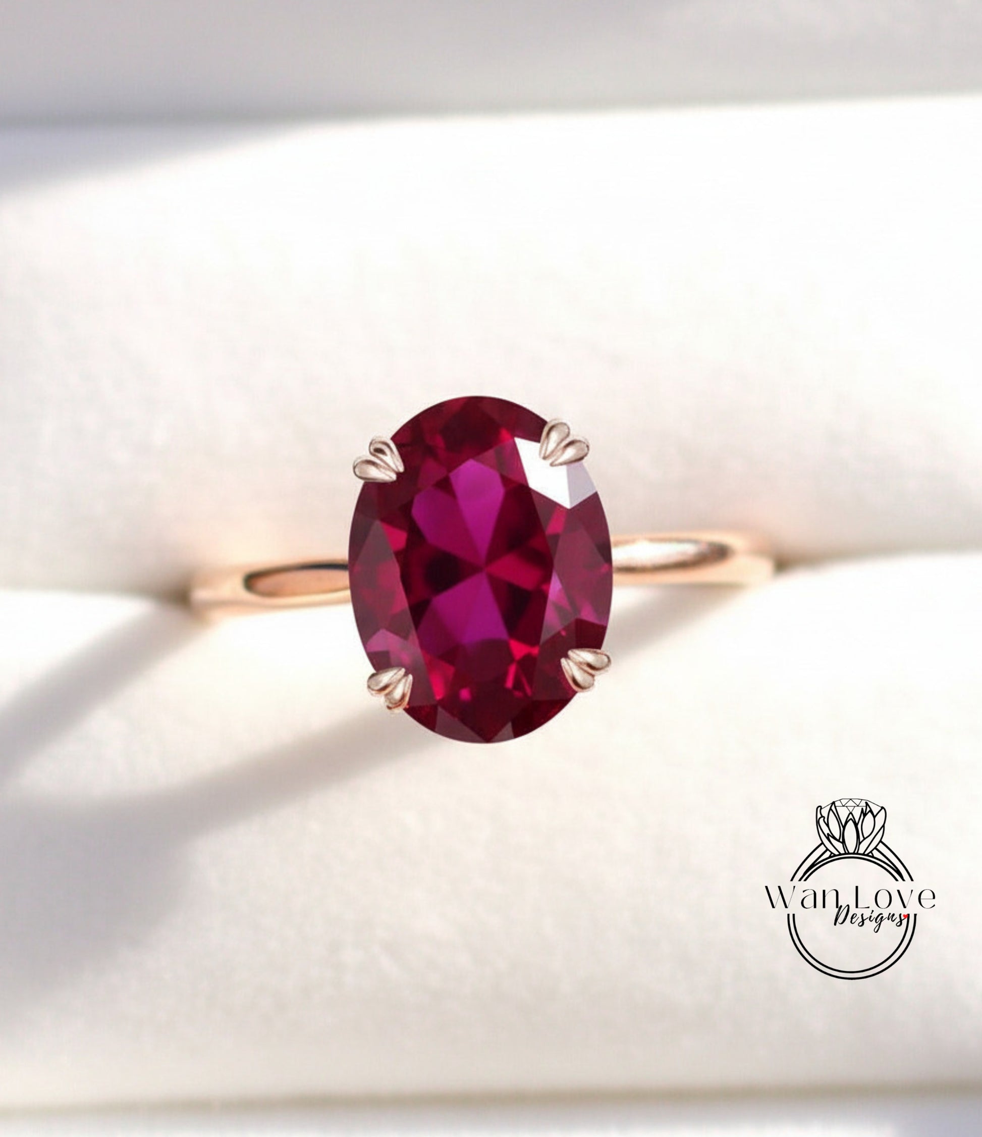 A close-up image of a gold ring with a large, deep red gemstone, likely a garnet, set in the center of the band.