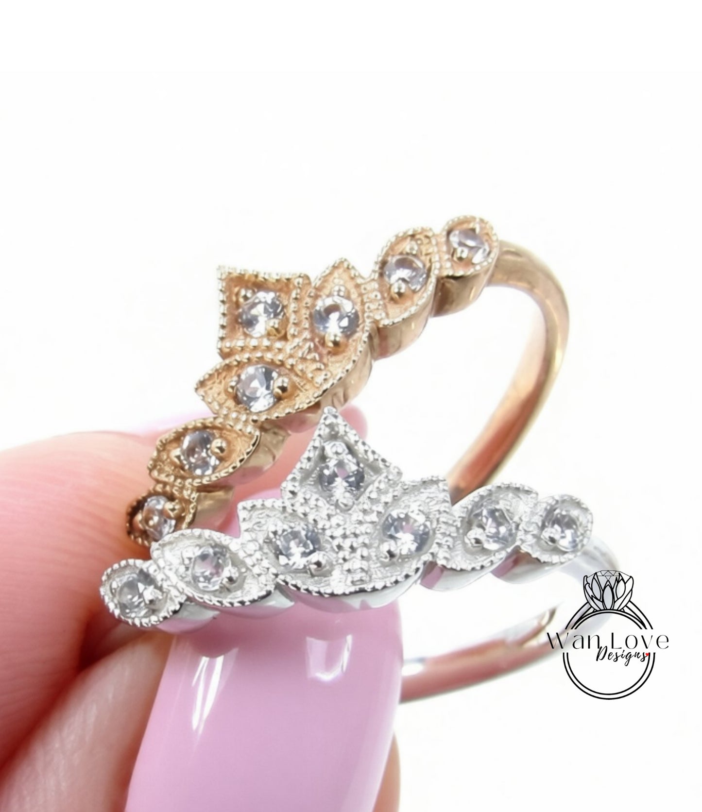 A close-up of a person's hand holding two rings with intricate designs and sparkling gemstones.