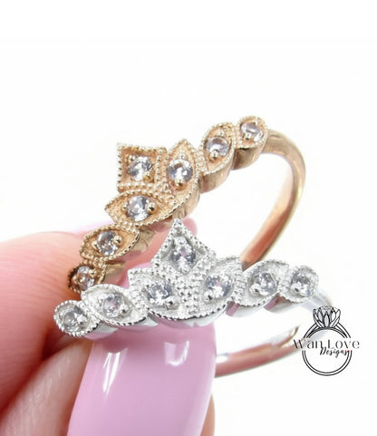 A close-up of a person's hand holding two rings with intricate designs and sparkling gemstones.