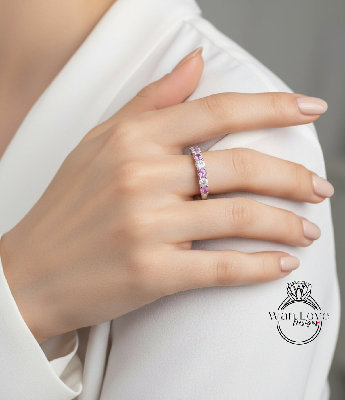 A close-up of a person's hand wearing a ring with pink gemstones.