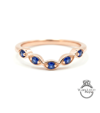 A rose gold ring with a row of blue sapphire gemstones set in the center.