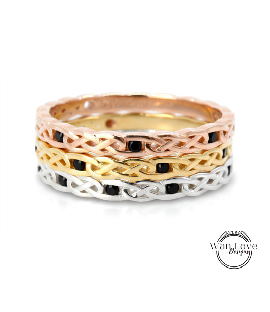 A ring with a braided design in various colors, including gold, silver, and black.