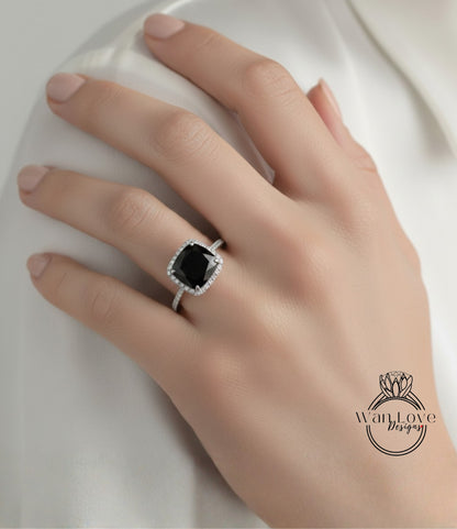 A close-up of a hand wearing a diamond ring with a large black gemstone.