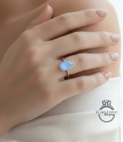 A close-up of a person's hand wearing a ring with a blue moonstone.