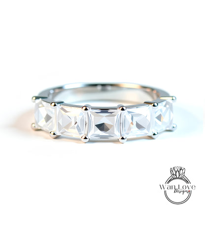 A close-up image of a silver ring with a row of clear gemstones, showcasing the intricate design and craftsmanship of the piece.