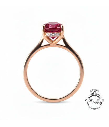 A rose gold engagement ring with a large, deep red gemstone set in the center.