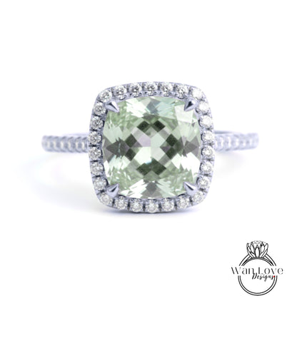A diamond ring with a large, square-cut green gemstone surrounded by a halo of smaller diamonds set in a silver band.