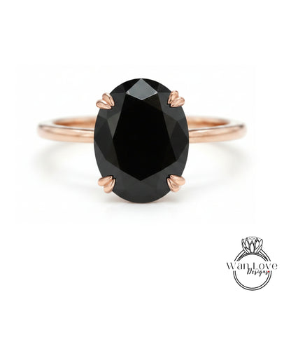 A rose gold ring with a large oval-shaped black gemstone set in the center.
