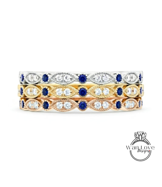 A three-tone ring with a gold band and a row of diamond-encrusted stones in various colors, including blue, yellow, and white.