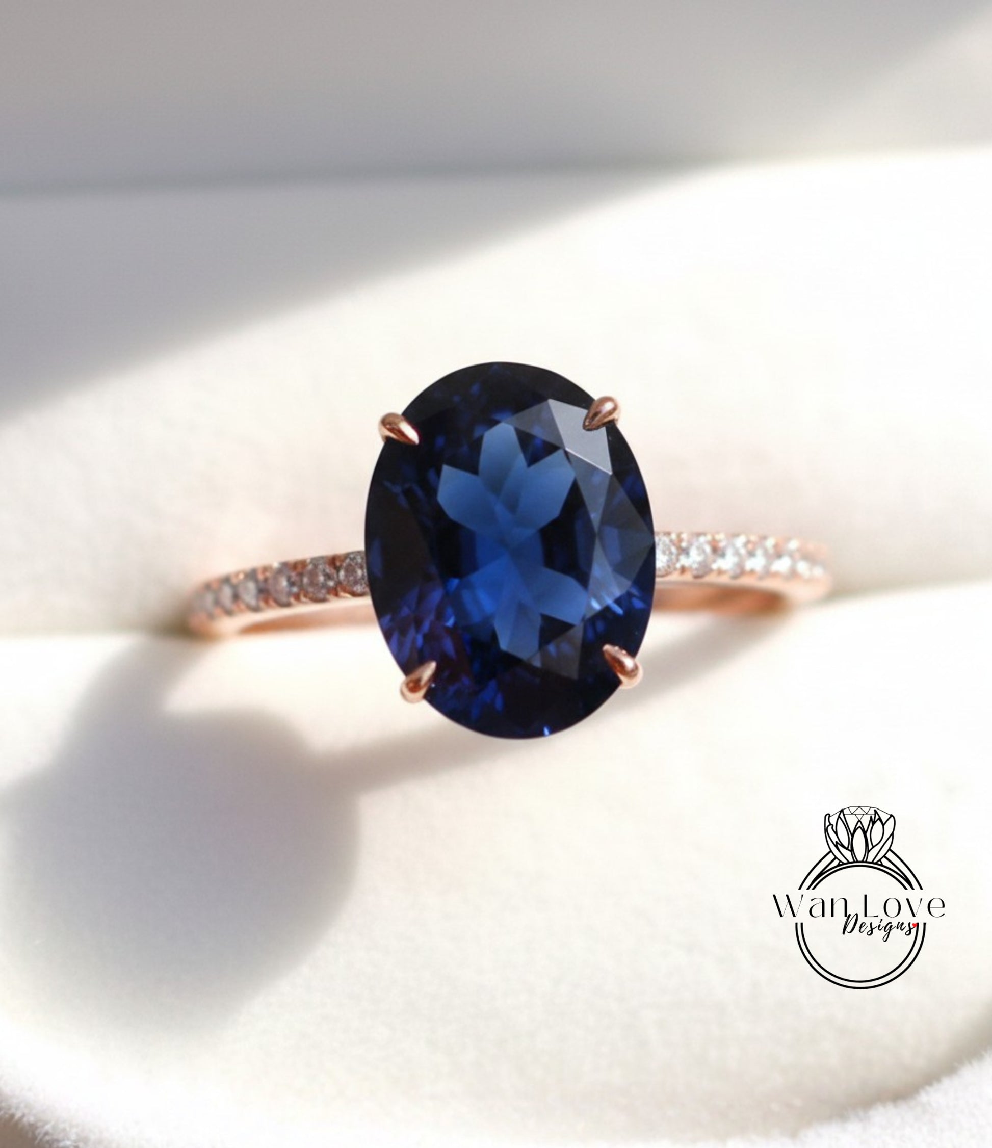 A close-up image of a rose gold ring with a large blue gemstone, likely a sapphire, set in the center.