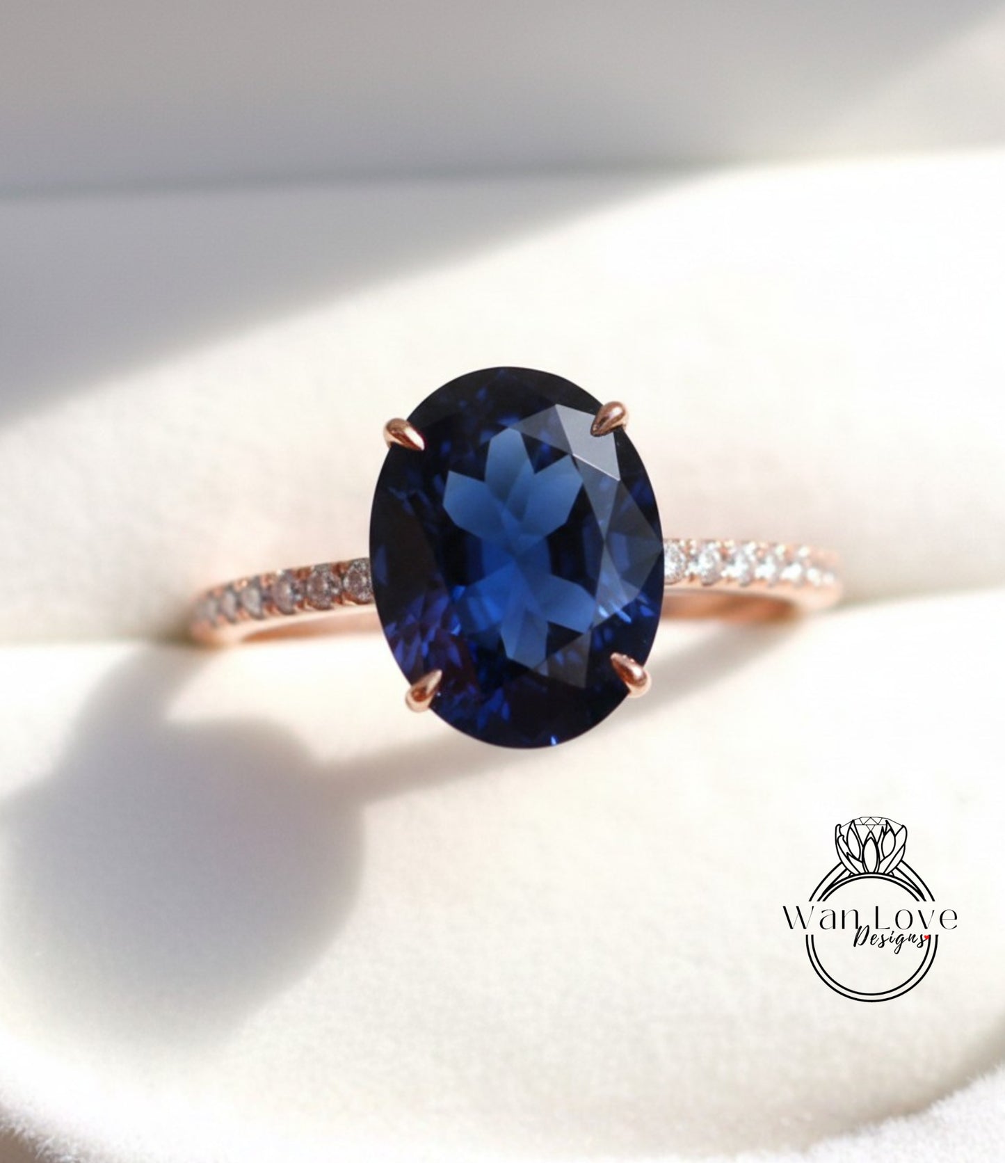 A close-up image of a rose gold ring with a large blue gemstone, likely a sapphire, set in the center.