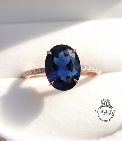 A close-up image of a rose gold ring with a large blue gemstone, likely a sapphire, set in the center.