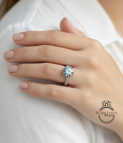 A close-up of a person's hand wearing a large diamond engagement ring.