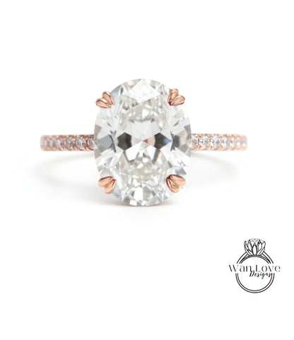 A large oval-shaped diamond engagement ring with a rose gold band and small diamonds set in the band.