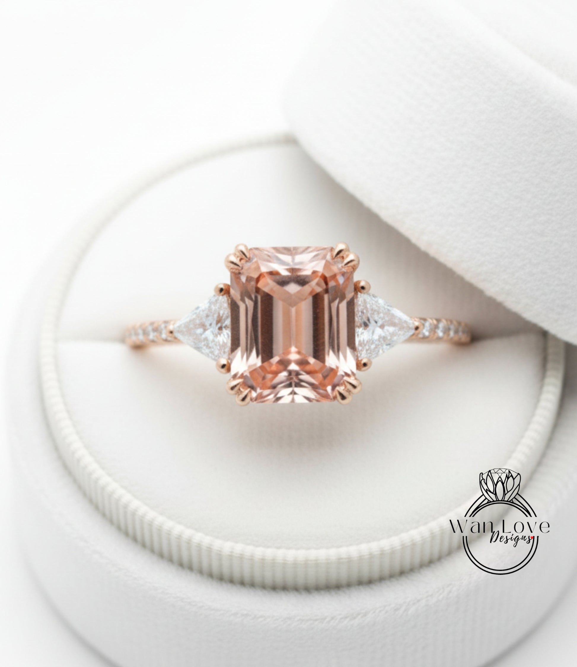 A close-up image of a beautiful engagement ring with a large, rectangular-shaped gemstone set in a rose gold band, placed in a white jewelry box.