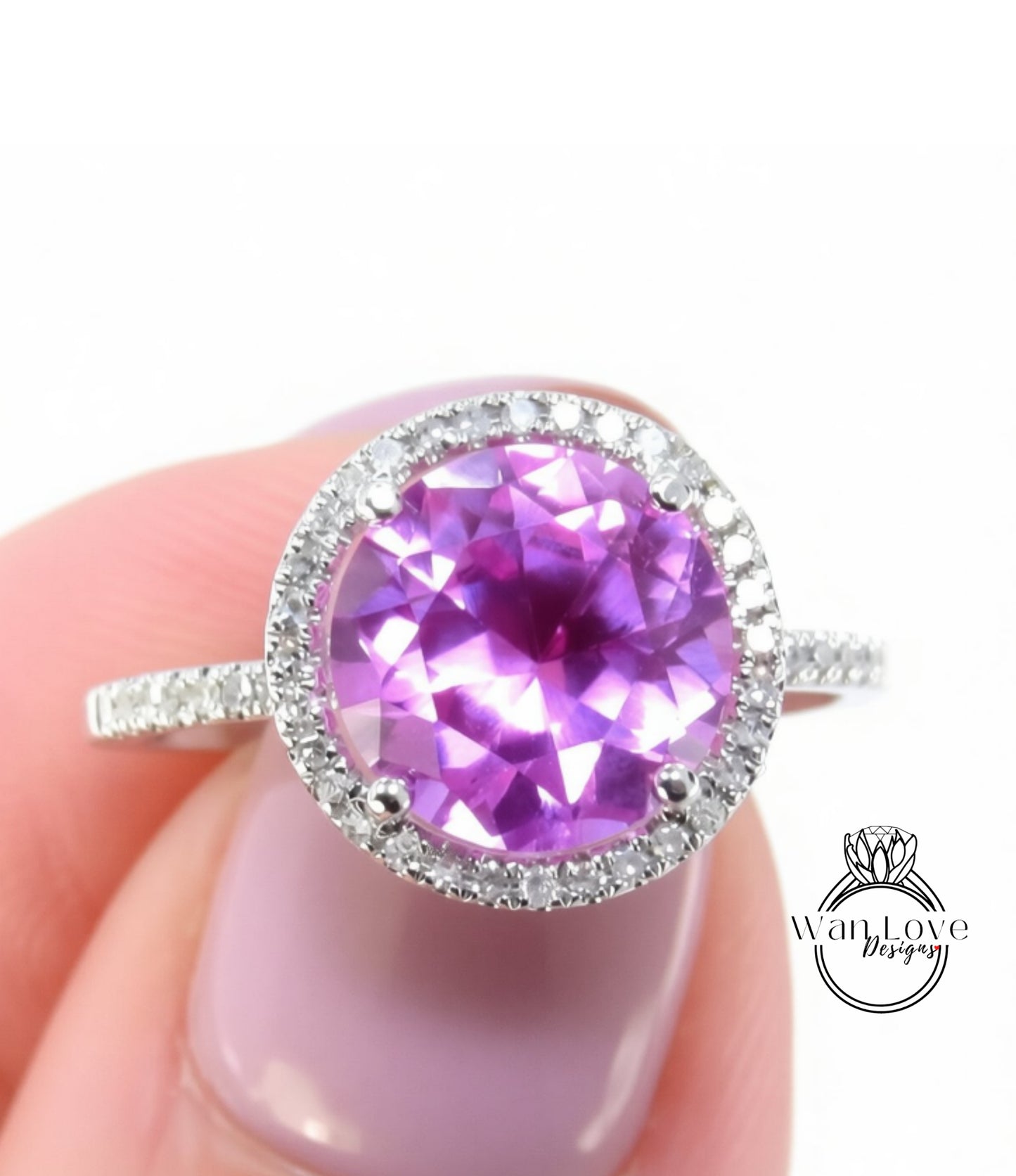 A close-up image of a person's hand holding a ring with a large, round purple gemstone surrounded by a halo of smaller diamonds.