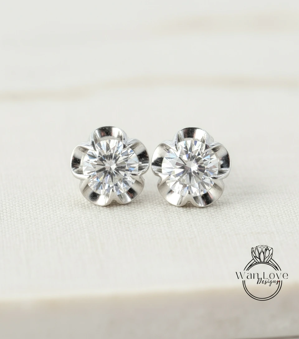 A pair of elegant diamond earrings with a large central diamond surrounded by smaller diamonds, resting on a white surface.