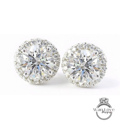 A pair of elegant diamond earrings with a large central diamond surrounded by smaller diamonds, set in a halo of smaller diamonds.