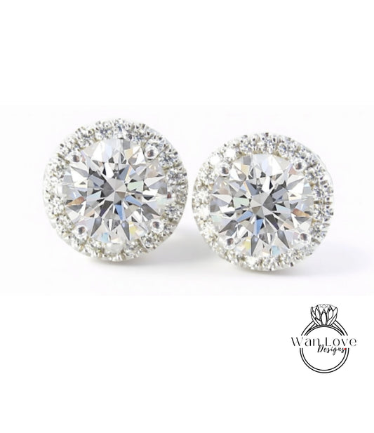 A pair of elegant diamond earrings with a large central diamond surrounded by smaller diamonds, set in a halo of smaller diamonds.
