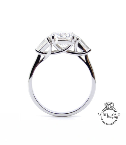 A silver engagement ring with a large central diamond surrounded by smaller diamonds on either side.