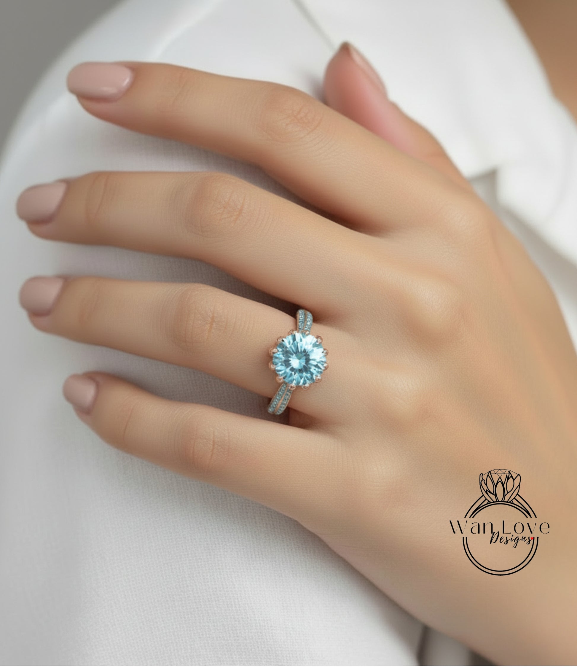 A close-up of a hand wearing a gold ring with a large blue gemstone, resting on a white surface.