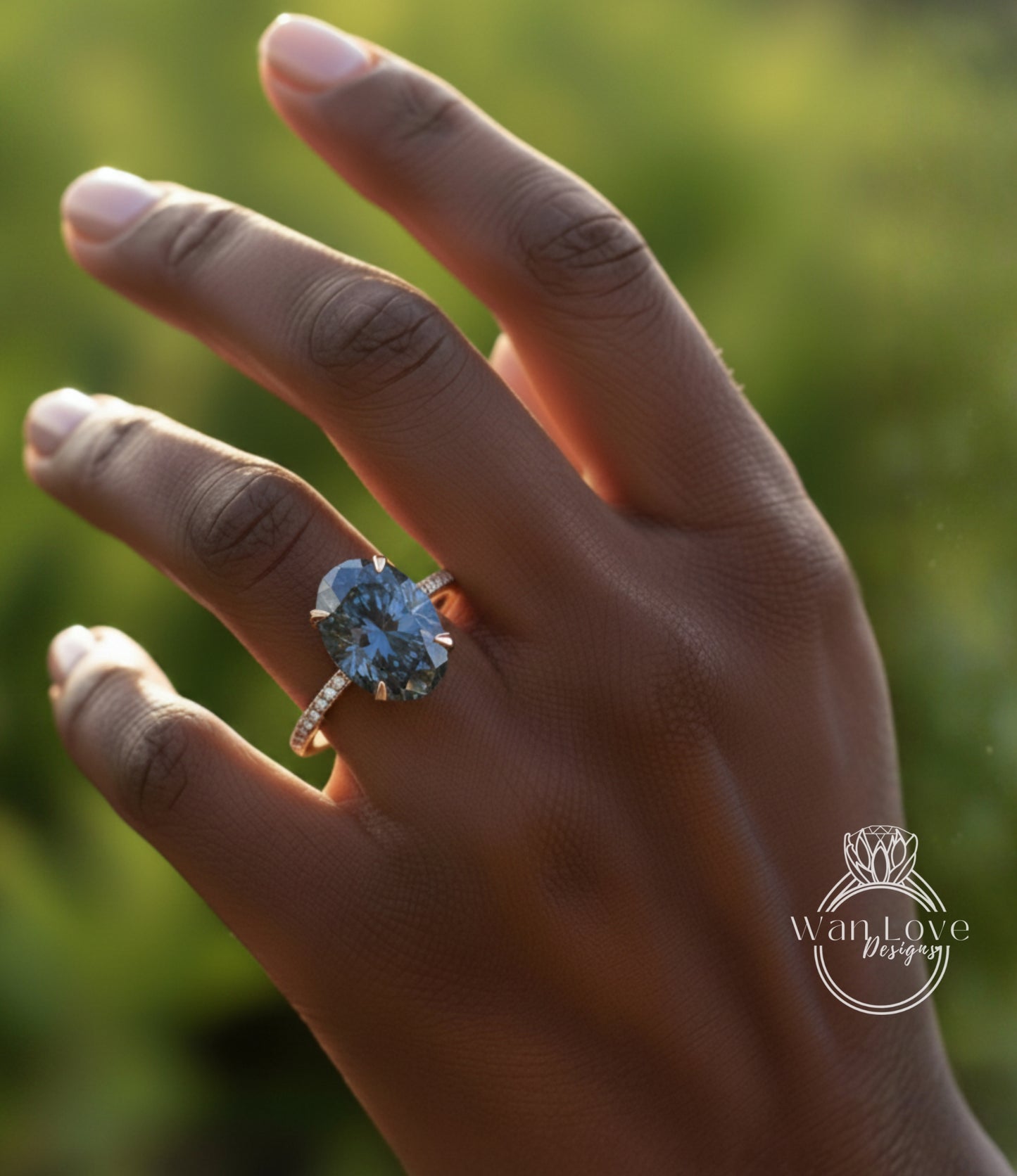 A close-up of a person's hand wearing a large, blue diamond engagement ring.