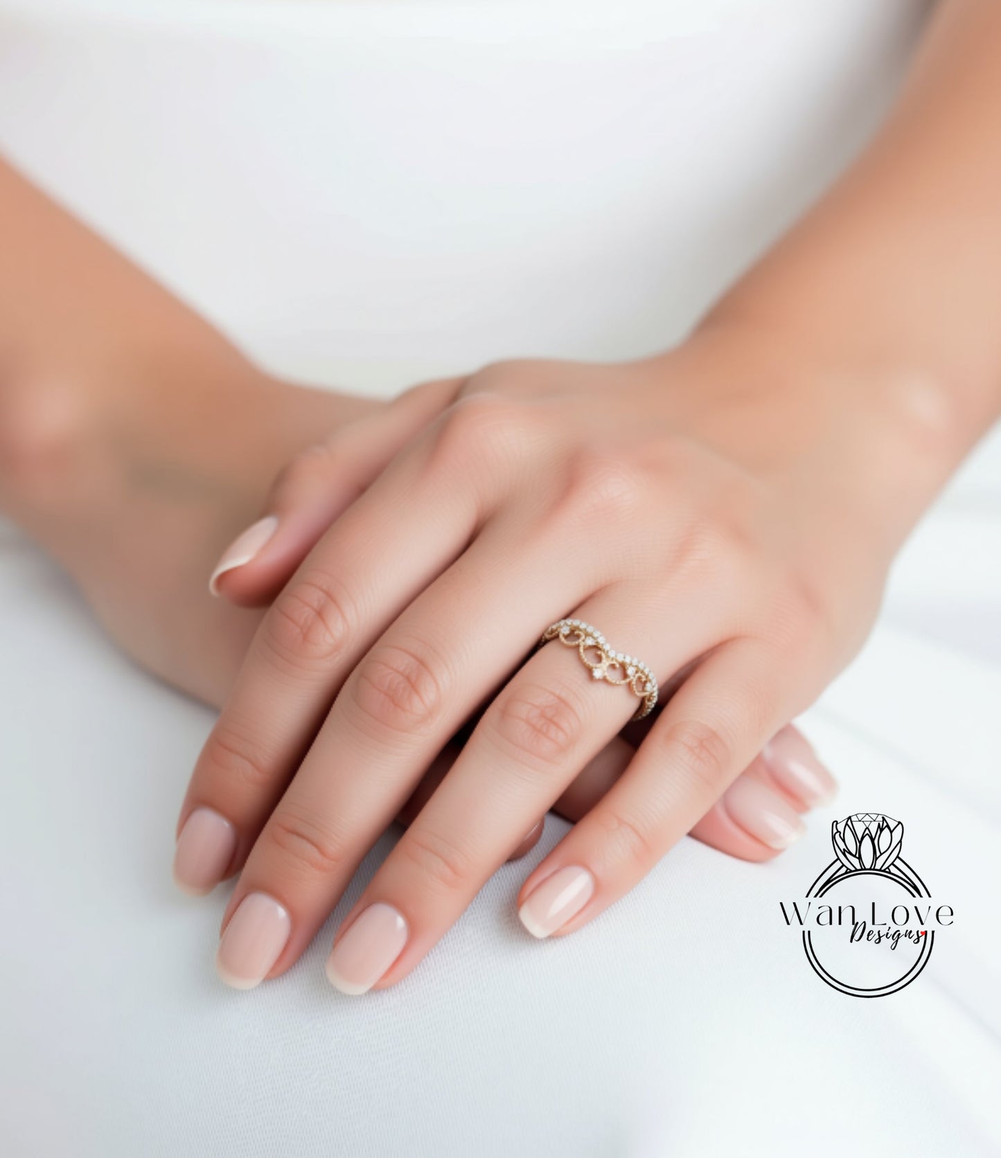 A close-up image of a person's hand wearing a ring, resting on a white surface.