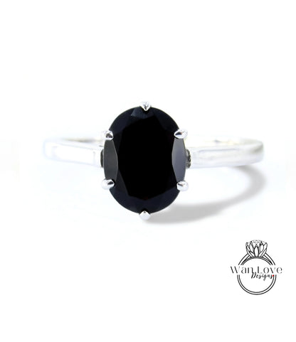 A silver ring with a large oval-shaped black gemstone, which appears to be a diamond.