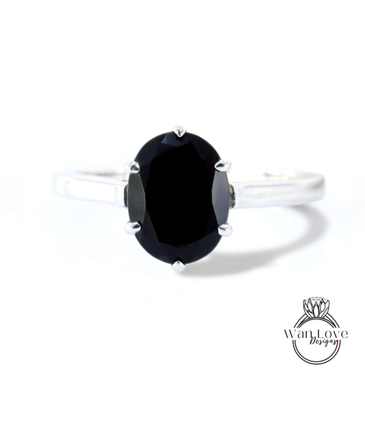 A silver ring with a large oval-shaped black gemstone, which appears to be a diamond.