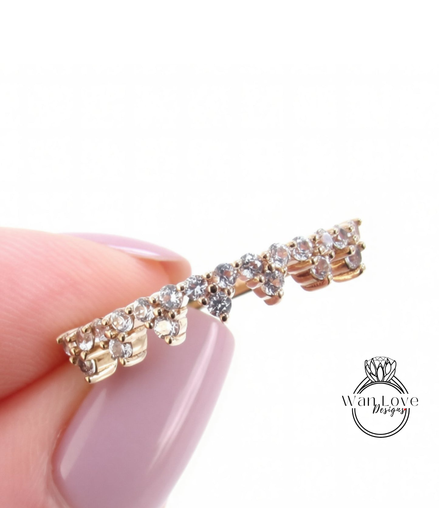 A close-up image of a person's hand holding a gold-colored ring with a row of small diamonds on it.