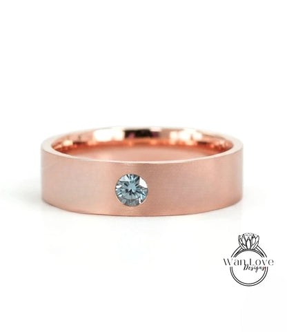 A rose gold band with a single blue gemstone set in the center.