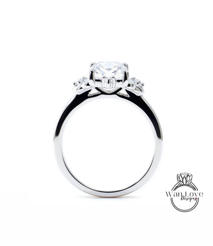A close-up view of a silver engagement ring with a large central diamond surrounded by smaller diamonds on either side.