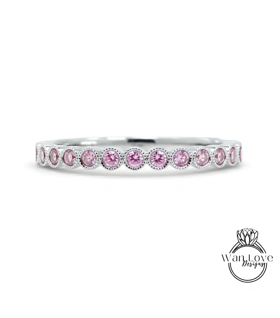A silver band ring with a row of pink diamonds set in it.