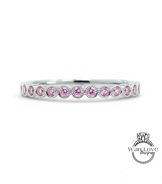 A silver band ring with a row of pink diamonds set in it.